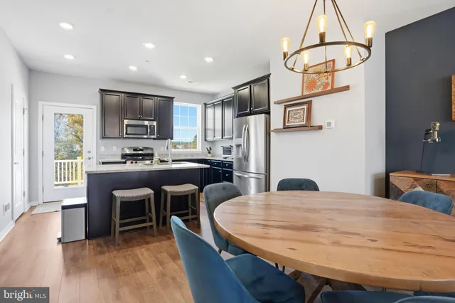 a kitchen with stainless steel appliances kitchen island a table chairs in it and wooden floors
