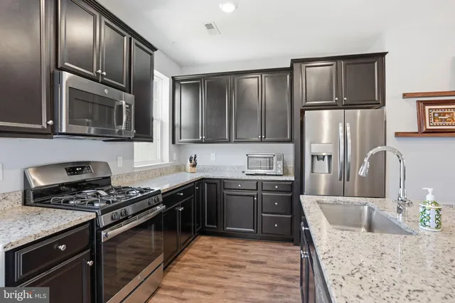 a kitchen with stainless steel appliances granite countertop a stove microwave and refrigerator