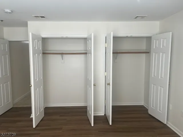 a view of an empty room with wooden floor & door
