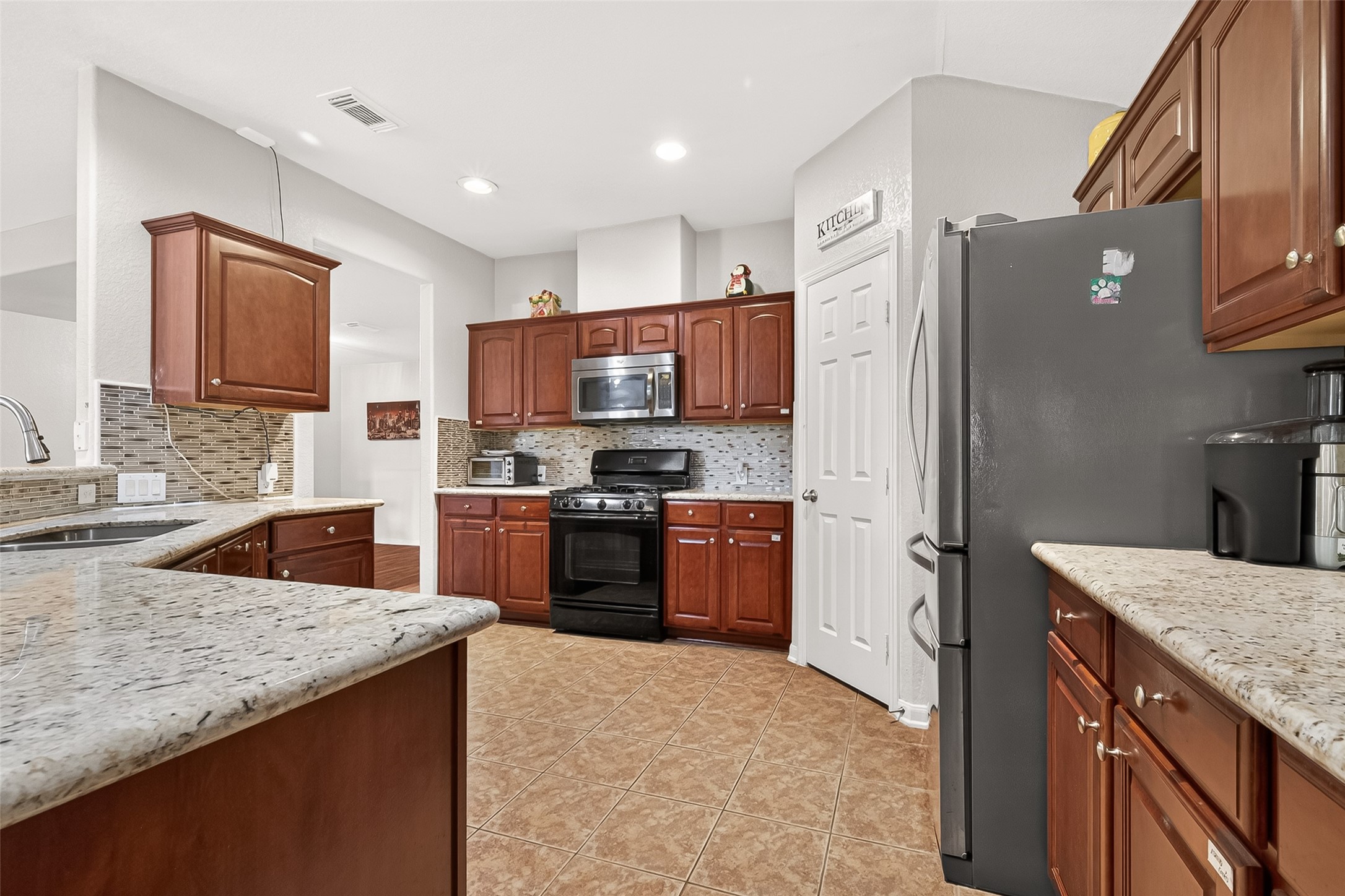 16715 Mackenzie Mesa Drive Spring, TX 77379 - Photo 15 of 50 a kitchen with granite countertop a refrigerator stove top oven and sink