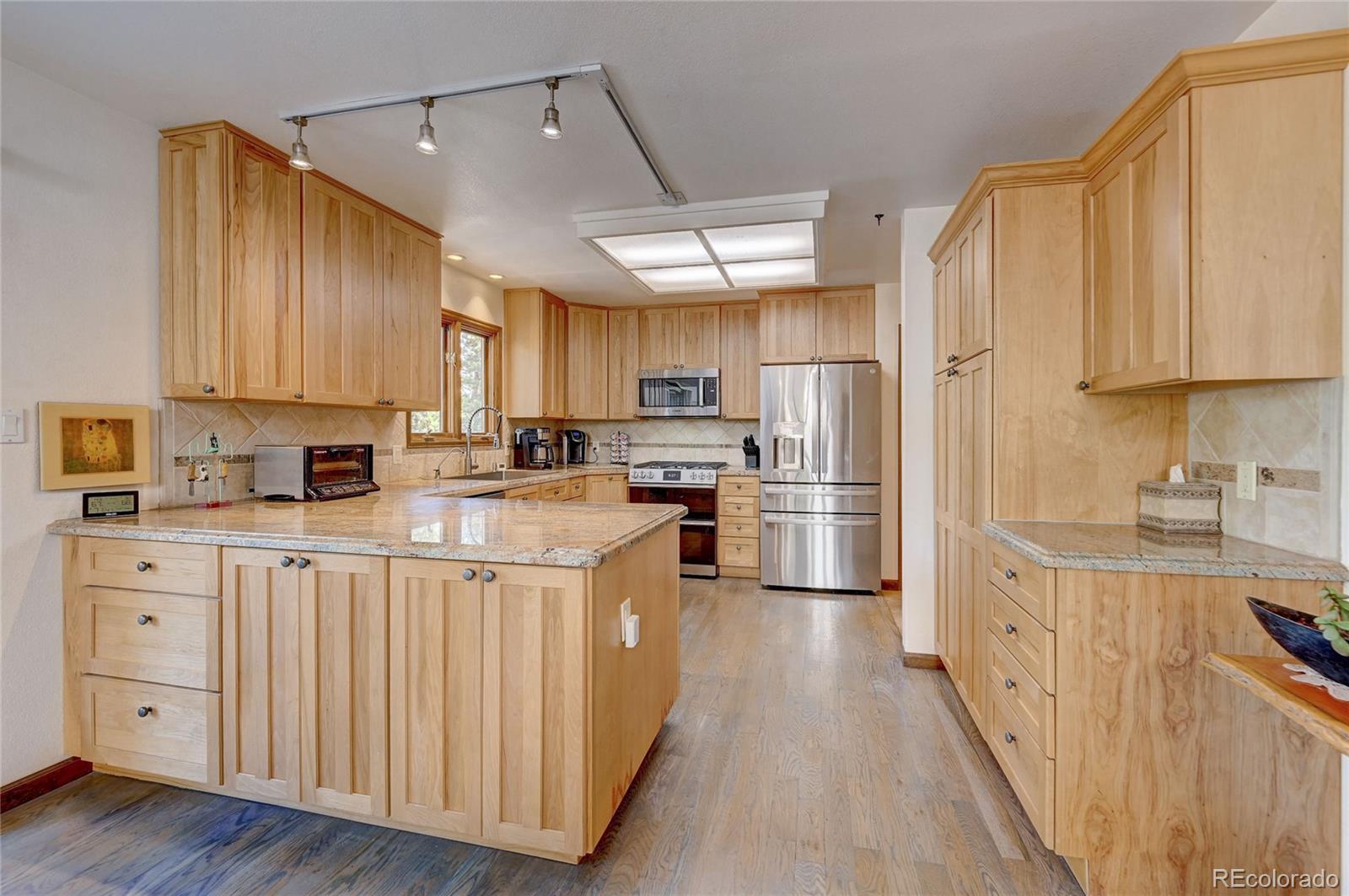 411 Spring Drive Pine, CO 80470 - Photo 18 of 40 a kitchen with stainless steel appliances granite countertop a refrigerator a stove top oven a sink and dishwasher with wooden floor