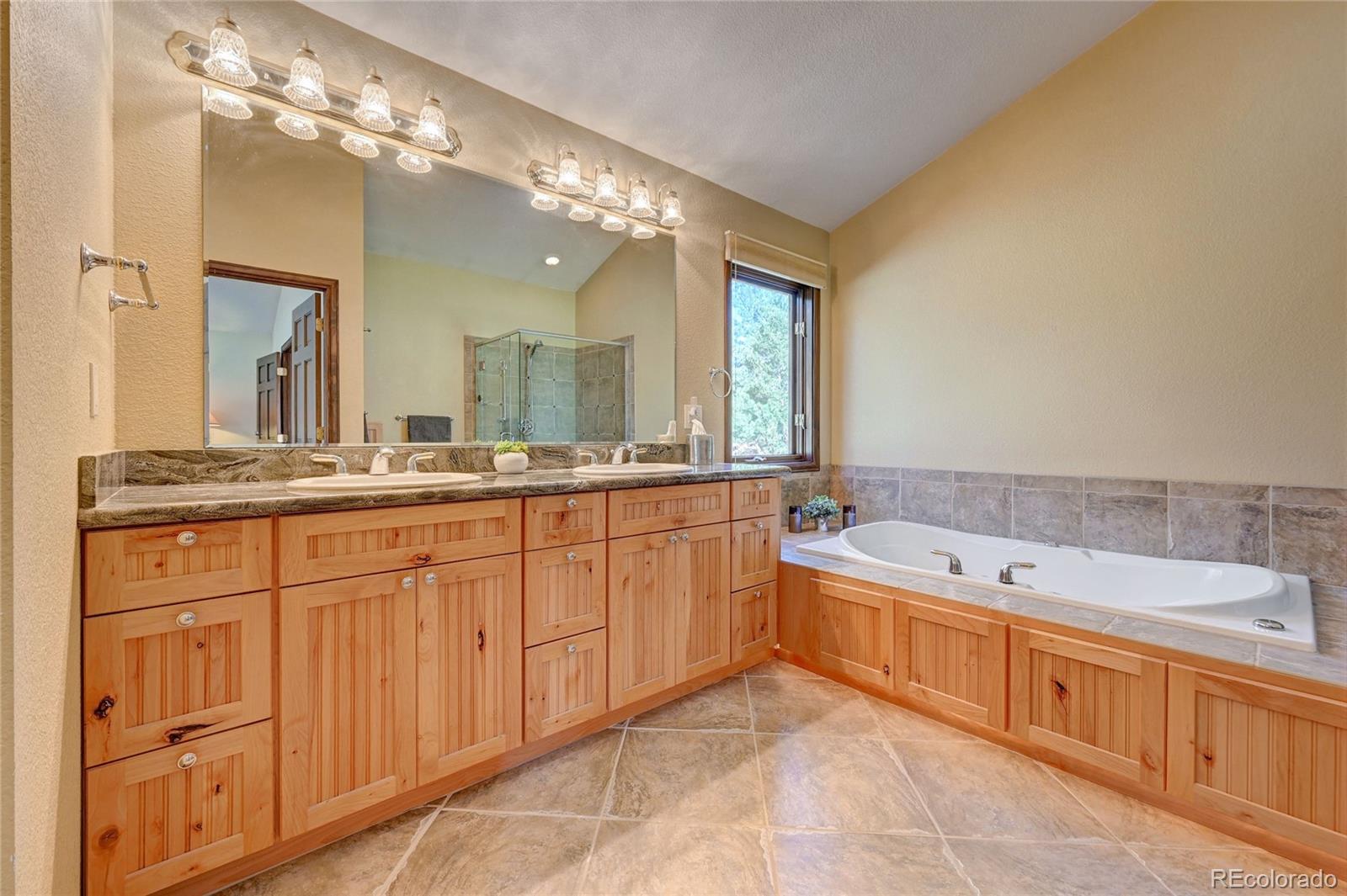 411 Spring Drive Pine, CO 80470 - Photo 33 of 40 a spacious bathroom with a granite countertop double vanity sink a mirror and a bathtub