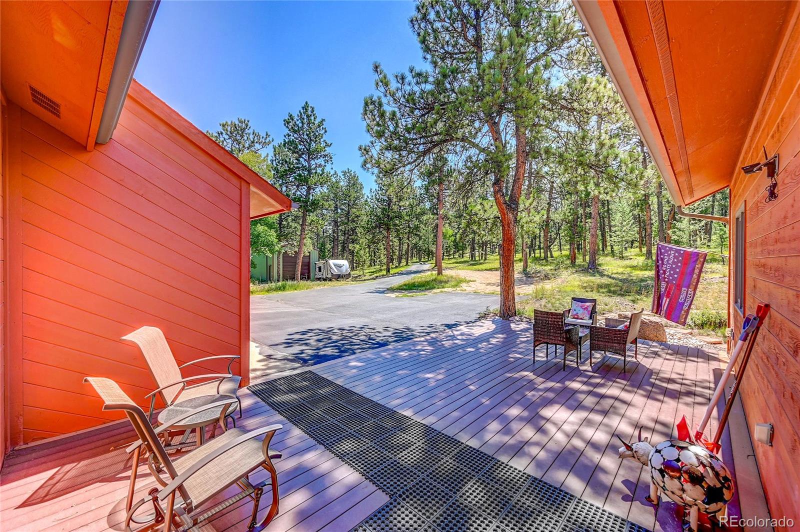411 Spring Drive Pine, CO 80470 - Photo 10 of 40 a view of a patio with table and chairs and couches with wooden floor and fence