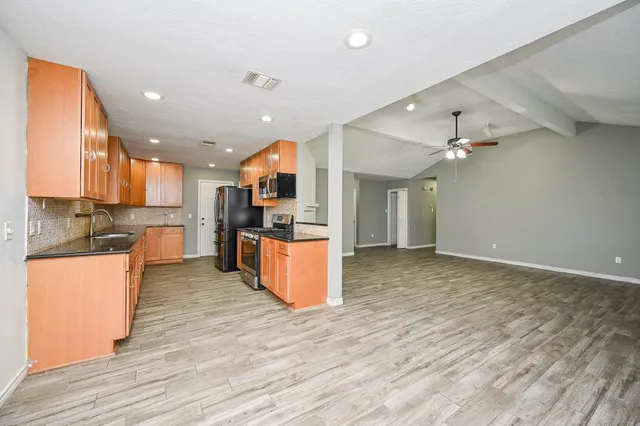 a large kitchen with stainless steel appliances kitchen island a large counter top and wooden floors