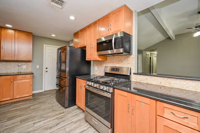 a kitchen with stainless steel appliances granite countertop a refrigerator a stove and a sink