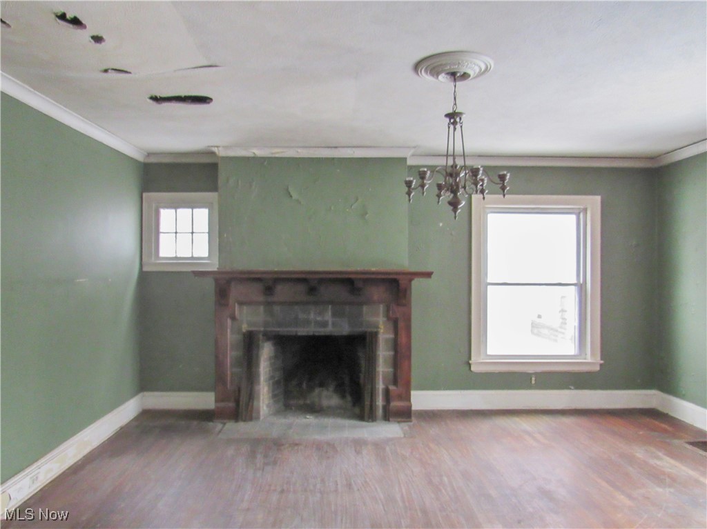 14450 Superior Road Cleveland, OH 44118 - Photo 3 of 35 Unfurnished living room featuring baseboards, ornamental molding, a brick fireplace, and wood finished floors
