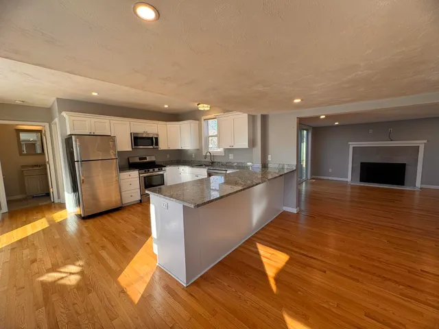 a large kitchen with stainless steel appliances granite countertop a large counter top a stove and a refrigerator