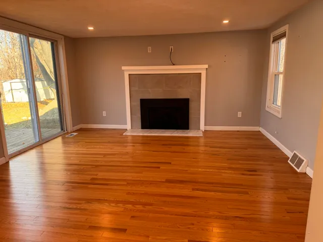 a view of an empty room with glass door and wooden floor