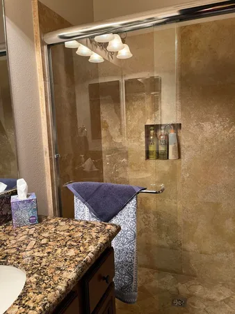 a bathroom with a granite countertop shower and a sink