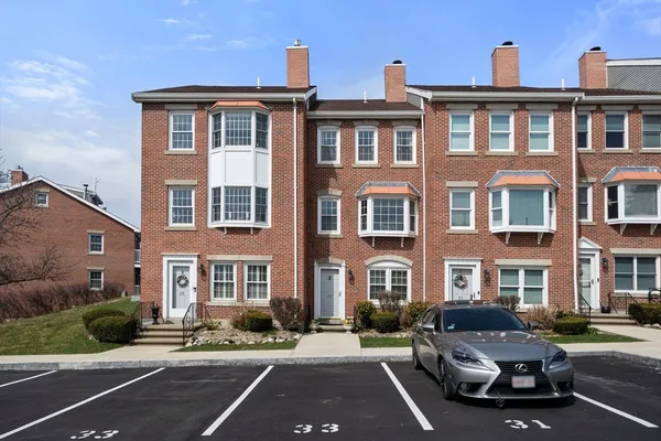 a front view of a building with lot of cars and trees