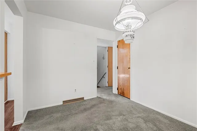 an empty room with a chandelier fan and wooden floor
