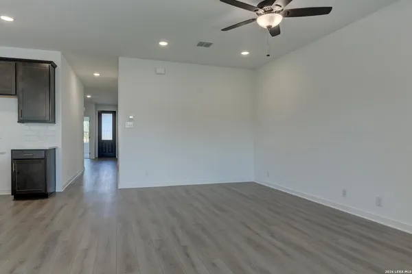 an empty room with wooden floor a ceiling fan a fireplace and windows