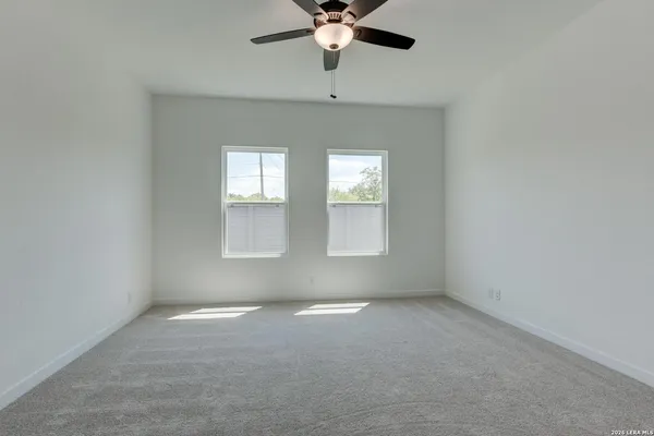 an empty room with a window and a chandelier fan
