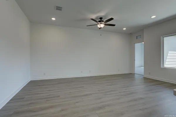 a view of an empty room with wooden floor and a window