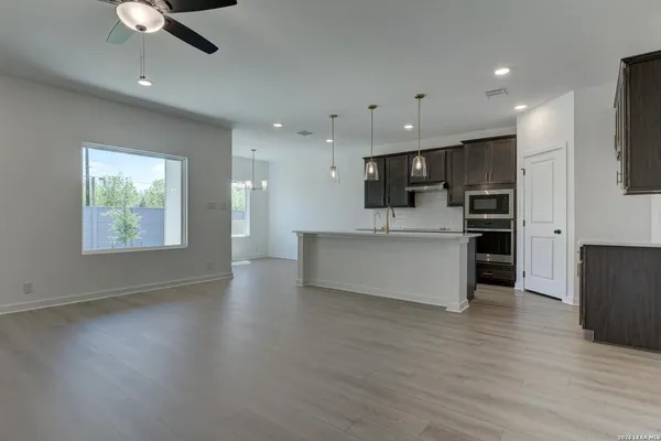 an open kitchen with kitchen island wooden floors appliances and cabinets