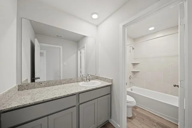 a bathroom with a granite countertop sink mirror toilet and bathtub