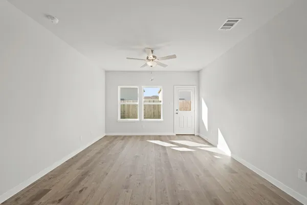 an empty room with wooden floor chandelier fan and windows