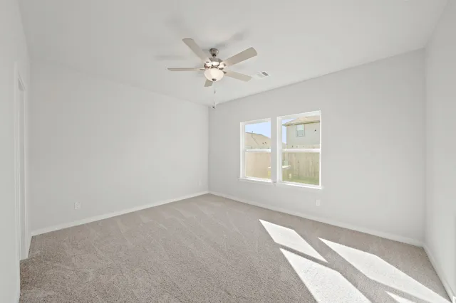 an empty room with windows and fan