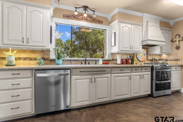 a kitchen with stainless steel appliances granite countertop white cabinets a sink and dishwasher with wooden floor