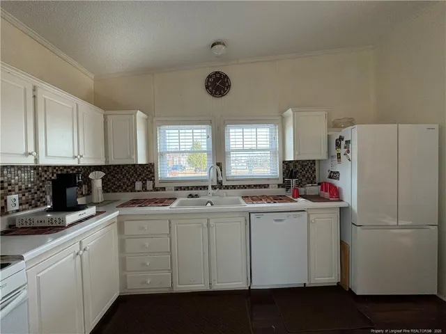 a kitchen with a sink a refrigerator a window and cabinets