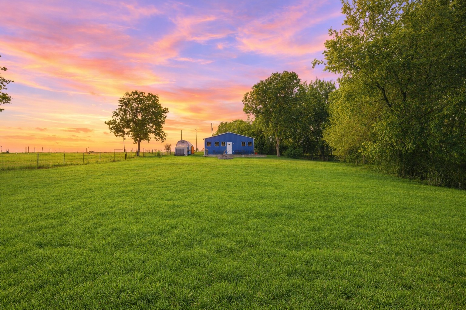 224 Old Coach Lane Elgin, TX 78621 - Photo 5 of 25 The property features a blue structure and a substantial green lawn, bordered by mature trees