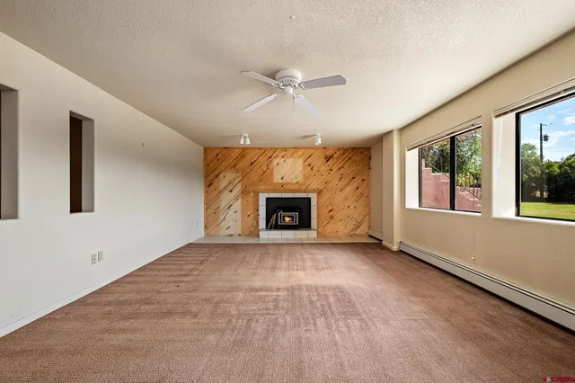 an empty room with windows and fireplace