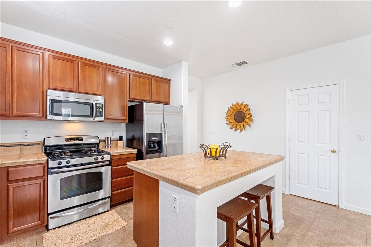 719 Courtyards Loop Lincoln, CA 95648 - Photo 11 of 33 a kitchen with stainless steel appliances a stove a sink a microwave and cabinets