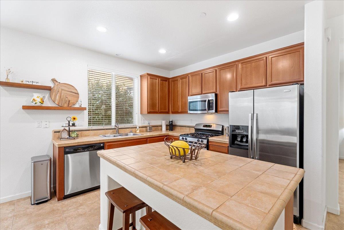 719 Courtyards Loop Lincoln, CA 95648 - Photo 12 of 33 a kitchen with a refrigerator a sink a stove and chairs