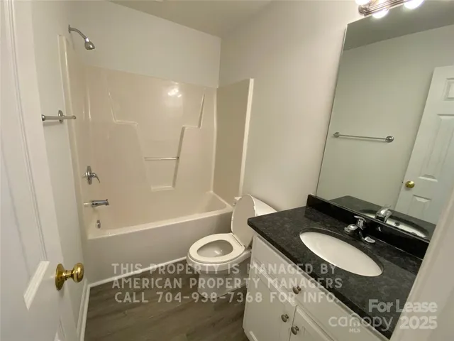 a bathroom with a granite countertop sink a toilet and shower