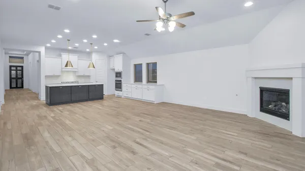 an empty room with kitchen and fireplace