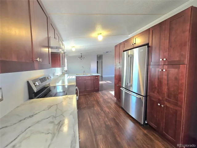 a kitchen with stainless steel appliances granite countertop a refrigerator a sink and wooden cabinets