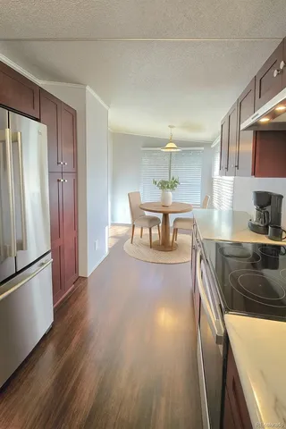 a kitchen with stainless steel appliances granite countertop a refrigerator a stove and a wooden floors