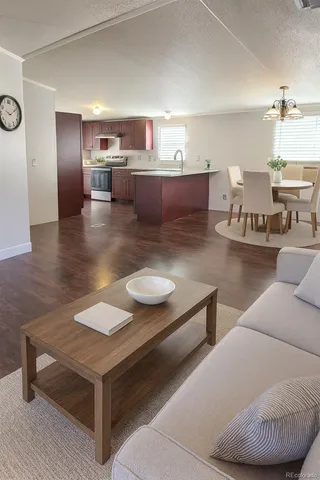 a living room with couches and kitchen view with wooden floor