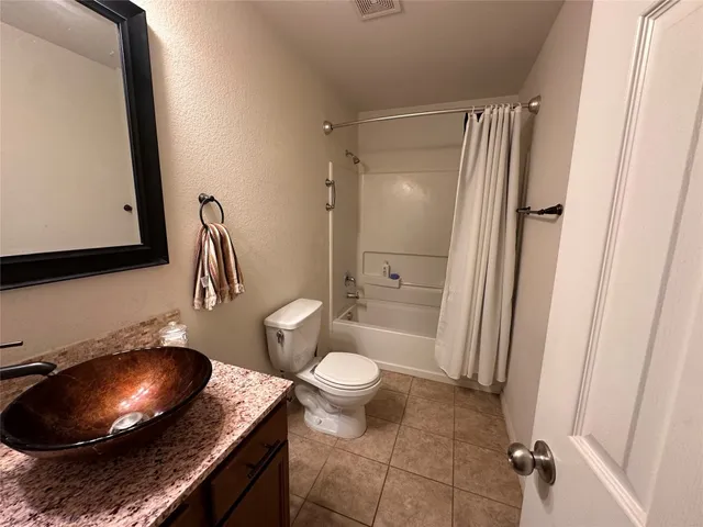 a bathroom with a granite countertop toilet sink and mirror