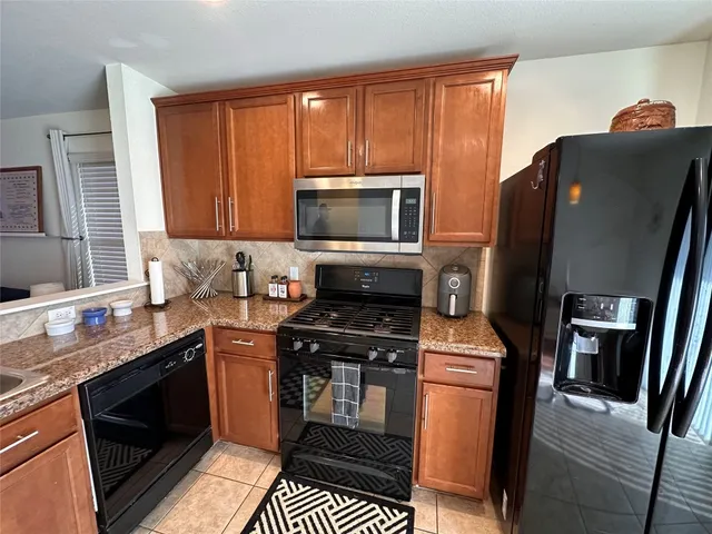 a kitchen with granite countertop a stove top oven microwave and refrigerator