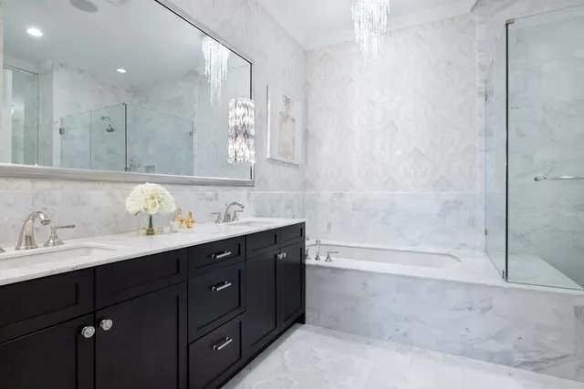 a bathroom with a tub sink double vanity and mirror