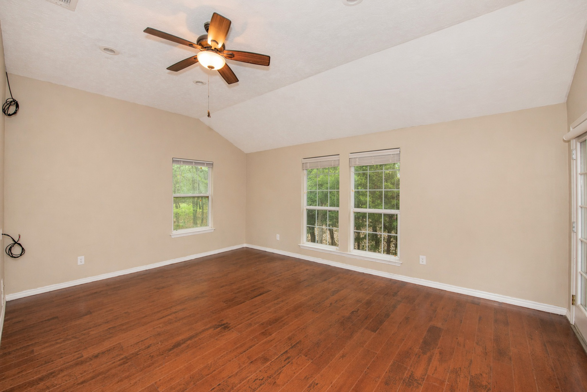 877 Hollow Bend Road, Unit 229 Caldwell, TX 77836 - Photo 12 of 18 an empty room with wooden floor ceiling fan and windows