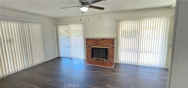 an empty room with wooden floor a ceiling fan and windows