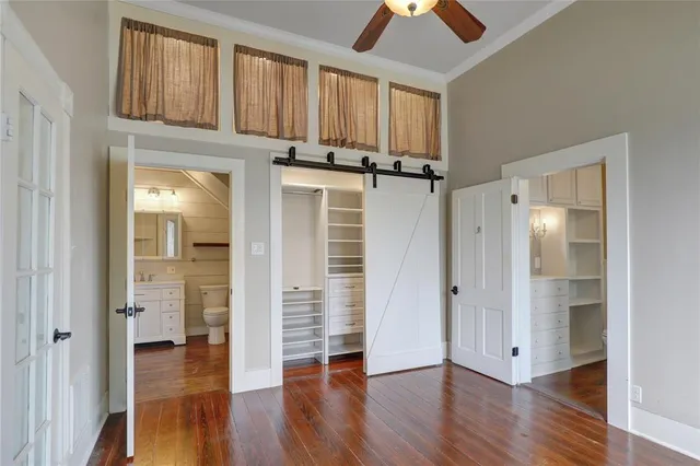 an empty room with wooden floor a ceiling fan and windows