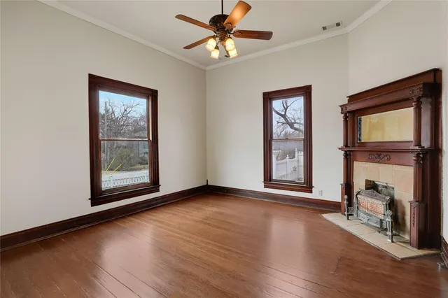 a view of an empty room with window fireplace and wooden floor