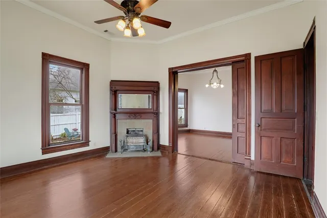 an empty room with wooden floor a ceiling fan and windows