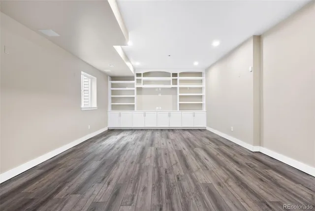 an empty room with wooden floor and window