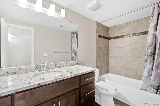 a bathroom with a granite countertop sink toilet mirror vanity and bathtub