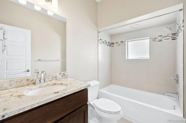 a bathroom with a granite countertop sink a toilet a mirror a bathtub and shower