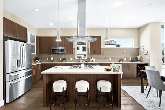 a kitchen with stainless steel appliances granite countertop a sink a stove and chairs