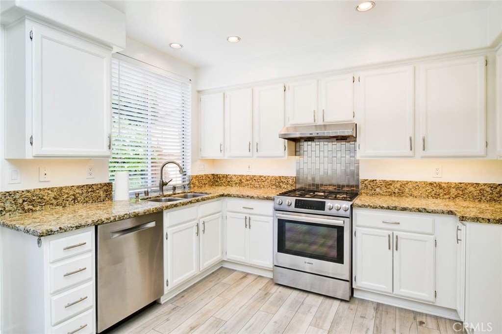 1 La Ronda Irvine, CA 92606 - Photo 12 of 29 a kitchen with granite countertop white cabinets and white appliances
