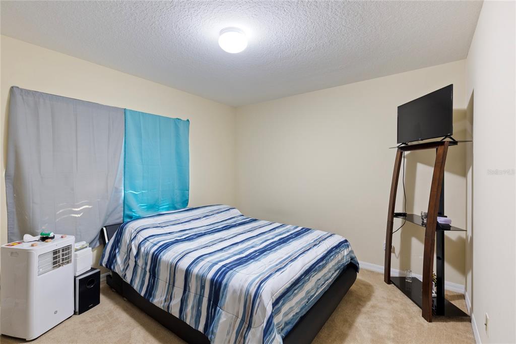 10901 Brickside Court Riverview, FL 33579 - Photo 21 of 36 a bedroom with a bed and a flat screen tv
