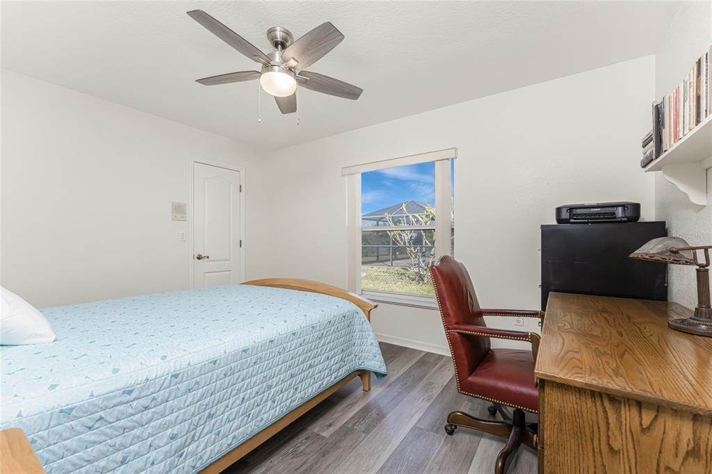443 Rotonda Circle Rotonda West, FL 33947 - Photo 27 of 59 a bedroom with a bed a desk and chair with wooden floor