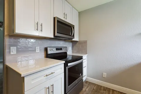 a kitchen with stainless steel appliances granite countertop white cabinets a microwave a sink and dishwasher