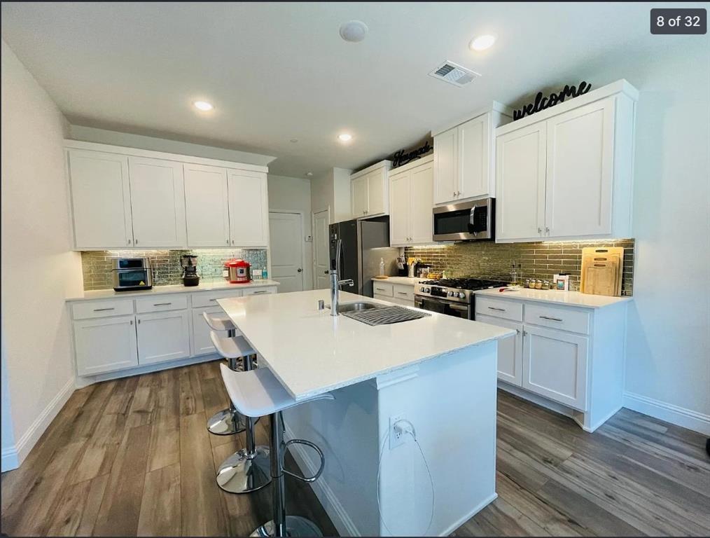 1009 Emil Place Allen, TX 75013 - Photo 8 of 31 a kitchen with kitchen island wooden floors appliances and center island